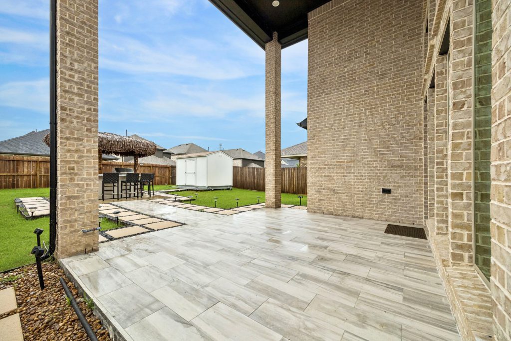 Backyard tiki hut, extended tile patio and lit paver walkway at 14 Savory Saute Dr in Harvest Green, Richmond TX